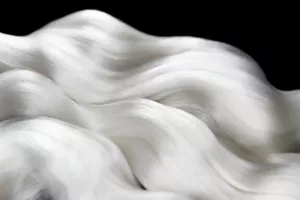 An abundant wave of silk thread shimmers and glows on a black background.